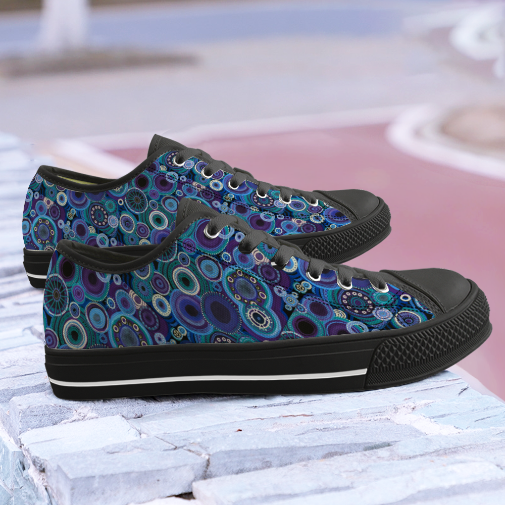 Pair Sneakers with black features and painted with thosands of interlocking circles of purple and teal.